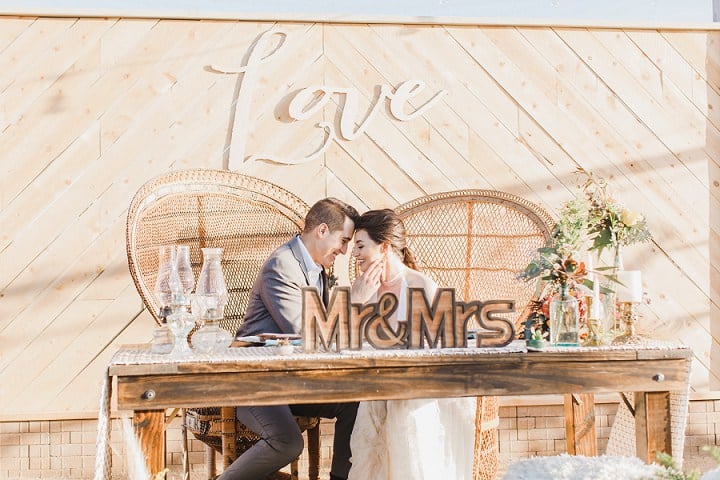 Newlyweds at a sweetheart table beneath a love sign